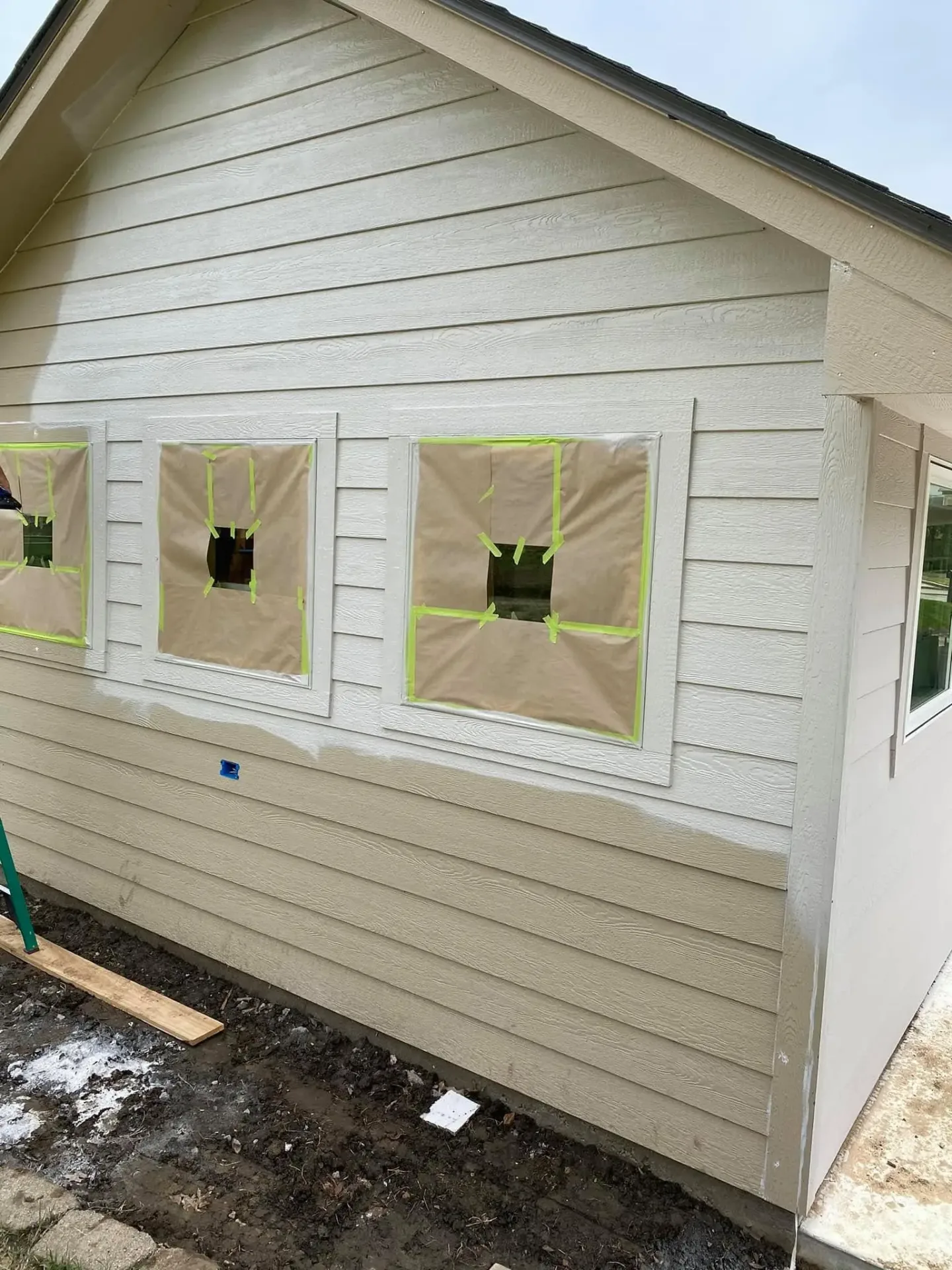 Freshly painted lap siding with masked windows on a Claremore, OK home
