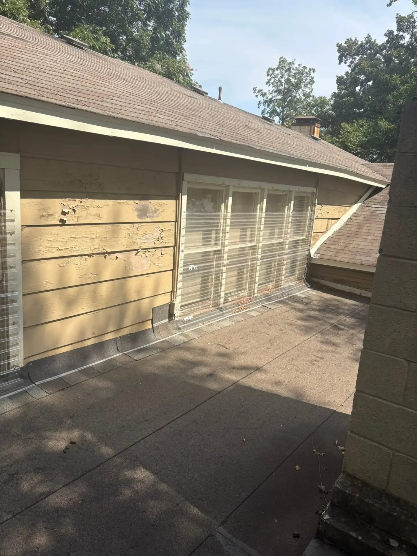 Hail-chipped yellow lap siding on a Claremore, OK home, documented from the roof by C&A Roofing & Construction
