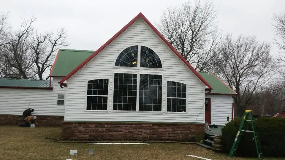 White lap siding on a Rogers County home with a red metal roof, installed by C&A Roofing & Construction