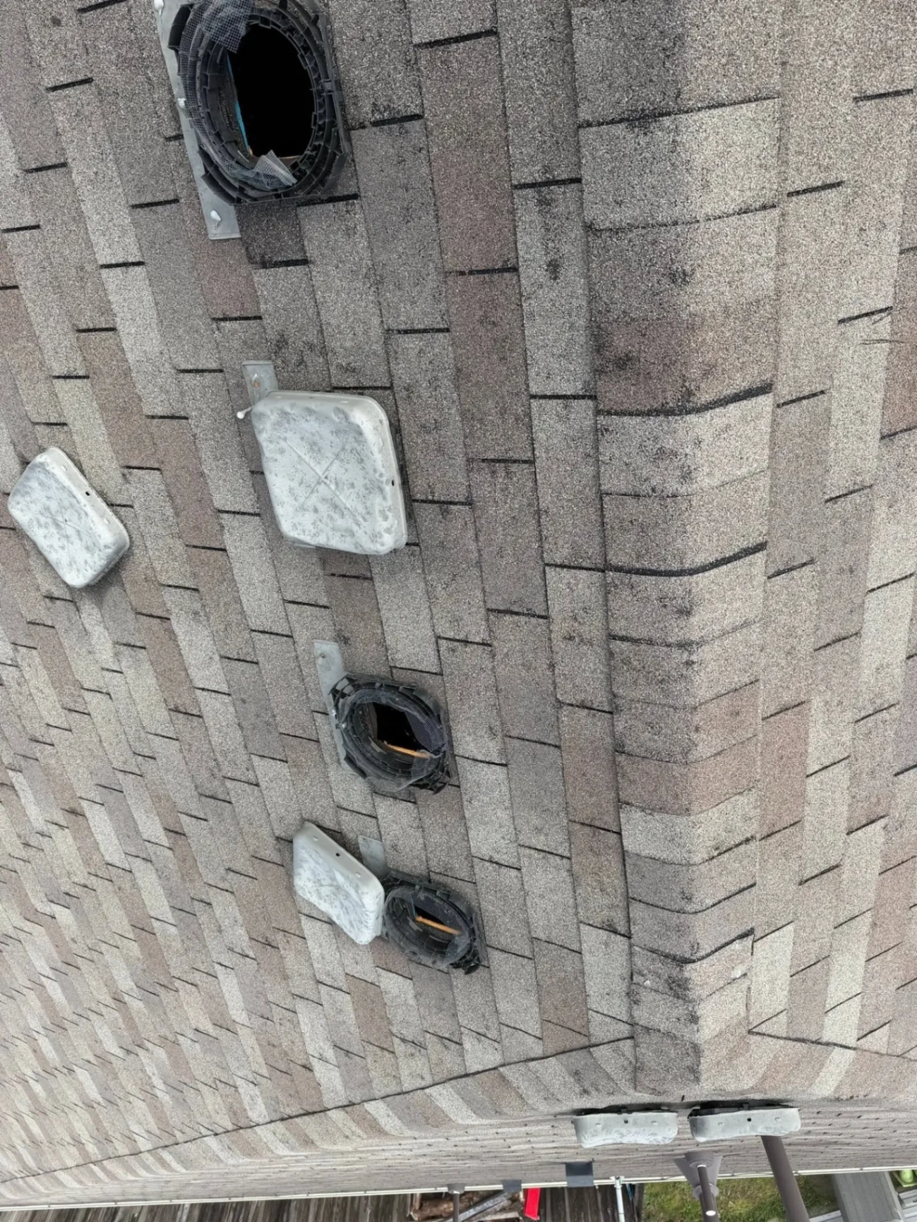 Cracked and dented plastic roof vents and bruised shingles from a Claremore, OK hail storm