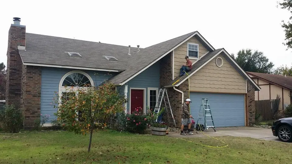 C&A crew repairing siding, gutters, and roofing on a blue two-story home in Tulsa County
